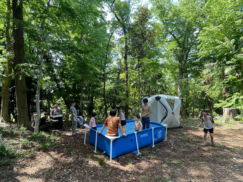 緑の木立のなかで子どもたちが水遊びを楽しむ夏の一日